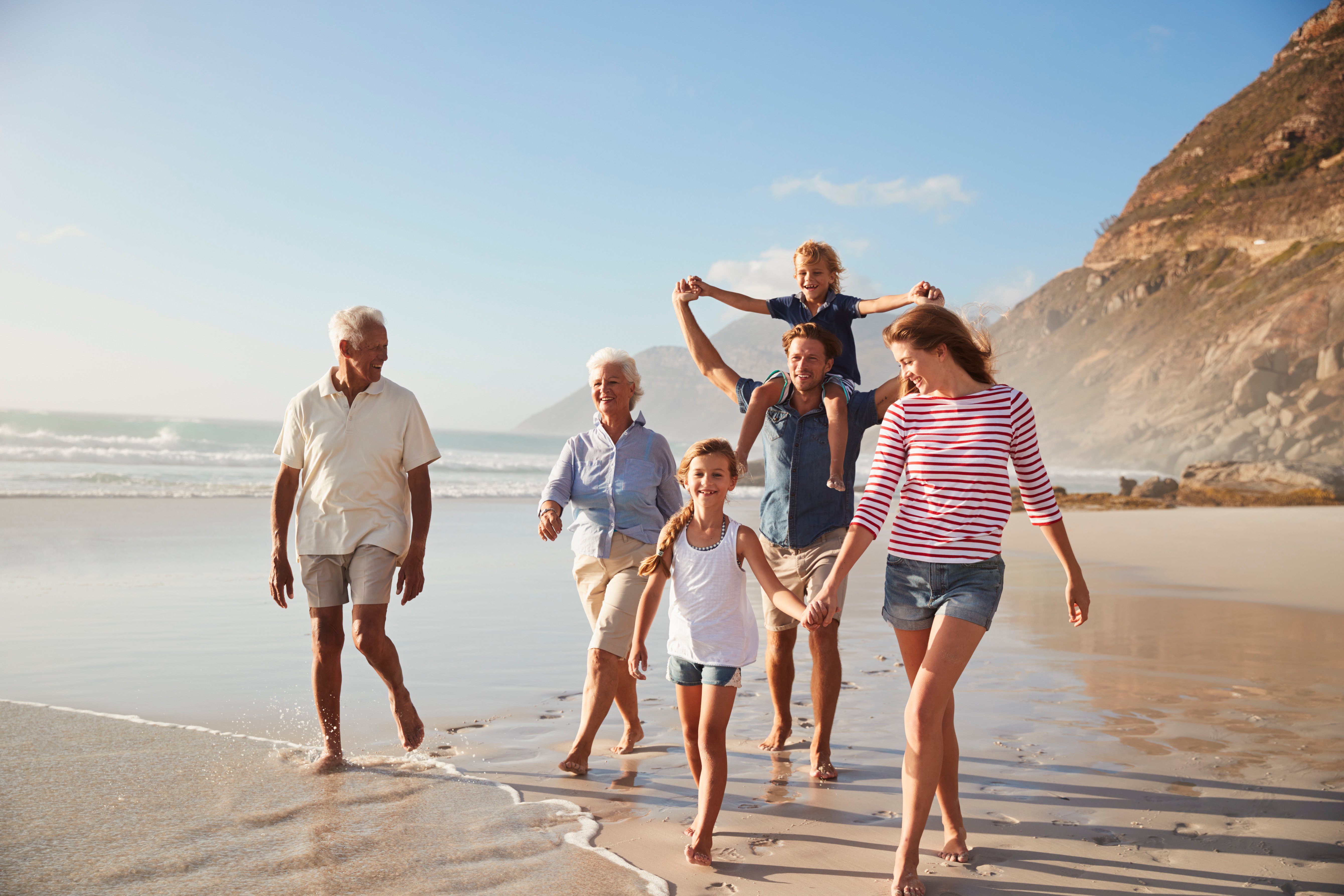 Multigenerational family walking together on the beach.